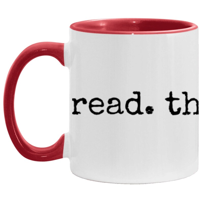 May include: White ceramic coffee mug with a red rim and handle. The mug has the text "read. the" printed in black.