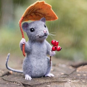 May include: A gray felt mouse holding a sprig of red berries under a brown felt leaf umbrella in the rain.