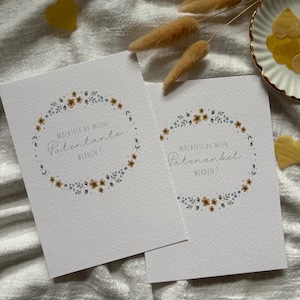 Könnte beinhalten: Zwei weiße Karten mit floralen Kranzdesigns und deutschem Text. Die Karten haben einen Aquarellstil mit braunen und blauen Blumen. Auf einer Karte steht "Möchtest du meine Patentante werden?" und auf der anderen "Möchtest du mein Patenonkel werden?"