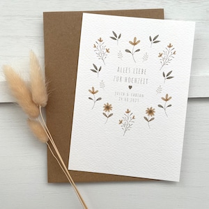 May include: A white card with a floral design and the text "Alles Liebe zur Hochzeit" with a heart symbol and the date "24.04.2023" and the names "Julia & Fabian".
