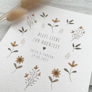 May include: A white card with brown floral illustrations and the text "Alles Liebe zur Hochzeit" with a heart symbol. Below the text is "Julia & Fabian 24.08.2023".