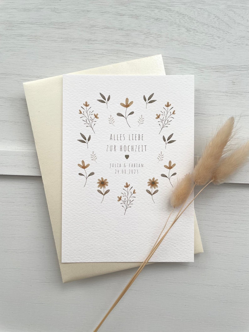 May include: A white card with a floral design and the text "Alles Liebe zur Hochzeit" with the date "July 08, 2023" and the names "Julia & Fabian".