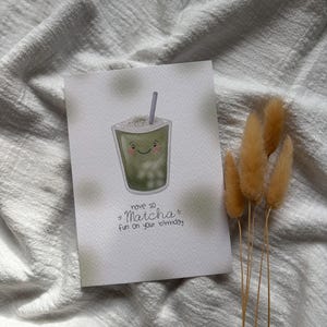 Puede incluir: Tarjeta de felicitaci&oacute;n de cumplea&ntilde;os con una ilustraci&oacute;n de bebida de matcha. La tarjeta presenta una bebida de matcha sonriente con una pajita y el texto "have so Matcha fun on your birthday". La tarjeta est&aacute; sobre un fondo blanco con un efecto acuarela verde claro.