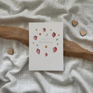 May include: A white card with a watercolor illustration of strawberries and flowers. The text "Happy Birthday" is written in gray script.