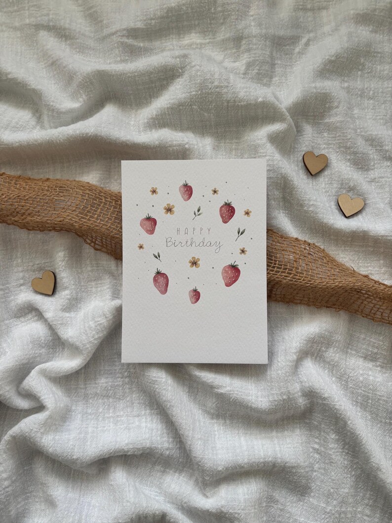 May include: A white card with a watercolor illustration of strawberries and flowers. The text "Happy Birthday" is written in gray script.