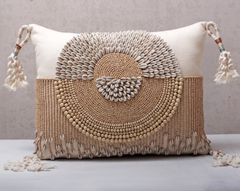 Funda de almohada lumbar color crema, cojín de algodón con conchas de kauri, borlas y cuentas de madera.