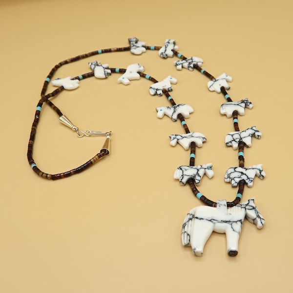 May include: A white and brown horse pendant necklace with turquoise accents. The necklace is made of brown beads and features multiple horse pendants.
