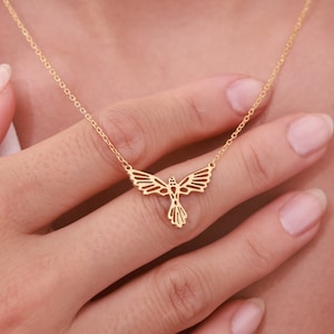 May include: A gold necklace with a delicate bird pendant. The bird is made of a thin metal and has a geometric design.