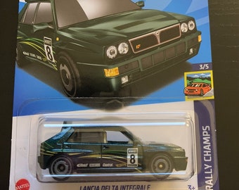 Könnte beinhalten: Ein grünes Hot Wheels-Spielzeugauto aus Druckguss, ein Lancia Delta Integrale, mit den Worten "Track Stars" und "Rally Champs" auf der Verpackung. Das Auto hat eine Nummer 8 an der Seite und die Worte "Lancia Delta Integrale" auf der Unterseite der Verpackung.