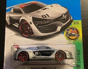 May include: A silver Hot Wheels die-cast toy car, a Renault Sport R.S. 01, with black accents and red wheels. The car is on a blue and green card with the Hot Wheels logo and the text "New! For 2016".