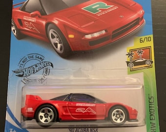 May include: A red 1990 Acura NSX die-cast toy car in a plastic blister pack. The car has black wheels and a black interior. The car is part of the Hot Wheels HW Exotics series and is numbered 163/250. The car is on a blue background with the Hot Wheels logo. The car has a "Ryula Circuit" sticker on the side.