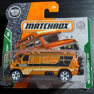 May include: A Matchbox 195 Custom Chevy Van toy car in orange and black with the words "Custom 95 Chevy Van" on the side. The car is on a green and orange card with the Matchbox logo and the words "Road Rip" and "65th Anniversary".