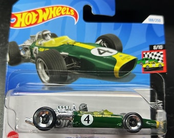 Könnte beinhalten: Grünes und gelbes Spielzeugauto Lotus Type 49 von 1967 in einer Hot Wheels-Verpackung. Das Auto hat eine Nummer 4 an der Seite und die Worte "Team Lotus" an der Seite. Die Verpackung hat einen blauen Hintergrund und die Worte "Hot Wheels" auf der Vorderseite.