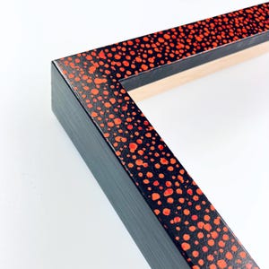 May include: Black picture frame with a red polka dot pattern on the outer edge.
