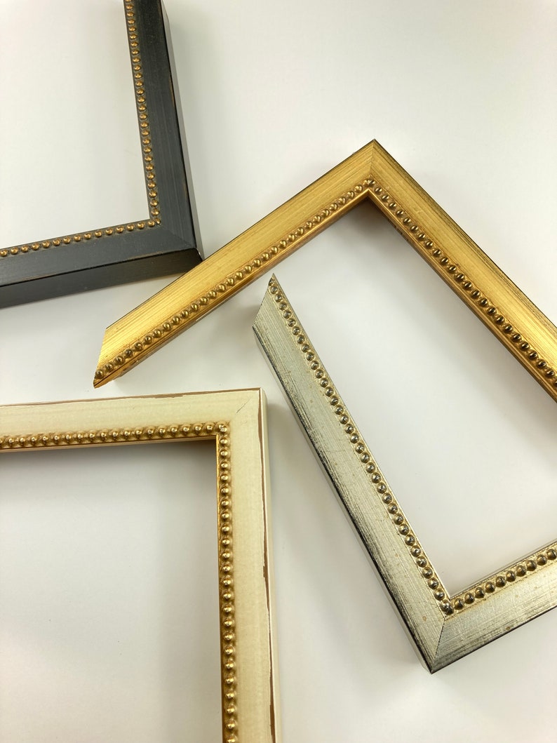 May include: Three picture frames with ornate gold beading. The frames are in different colours: black, white and silver.