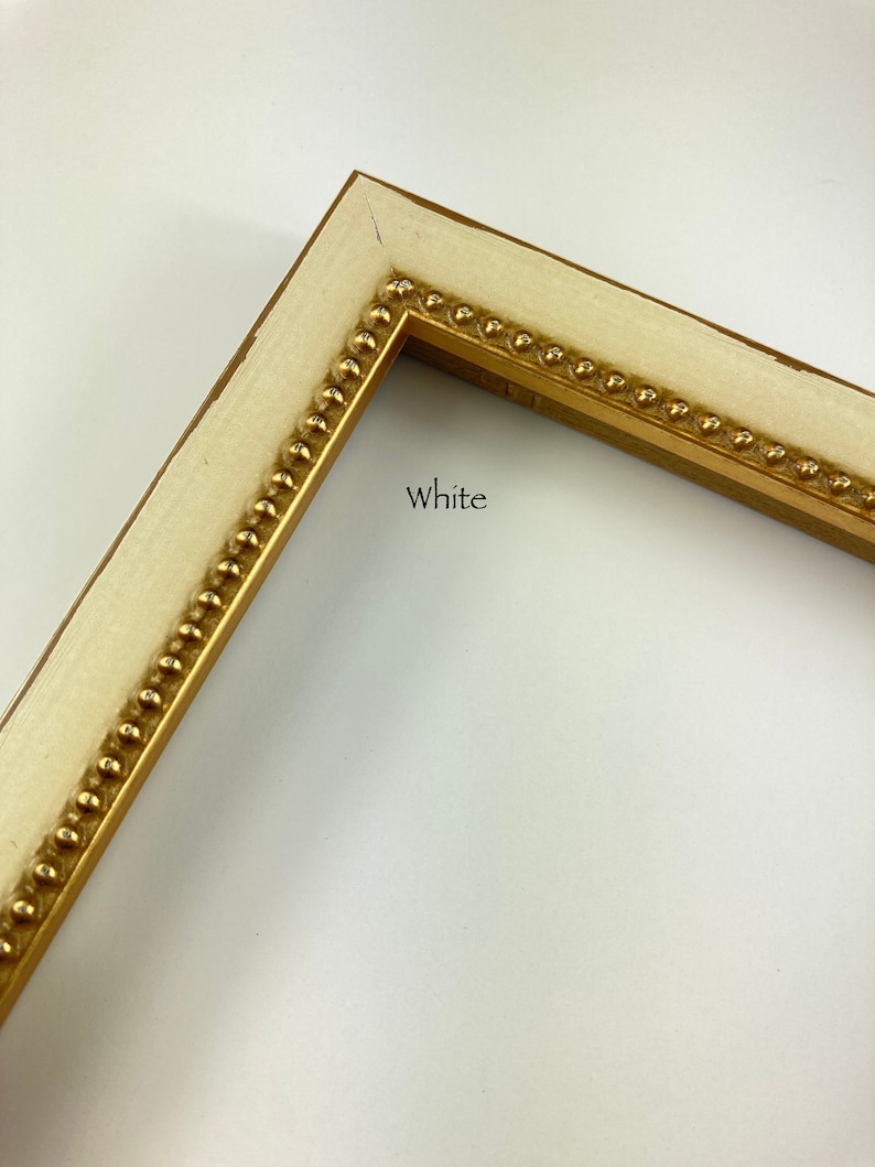 May include: White picture frame with a gold beaded trim. The frame is made of wood and has a simple, classic design.