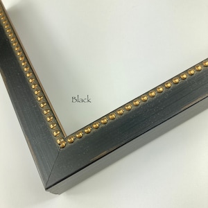 May include: Close-up of a black picture frame with gold accents. The frame has a distressed finish and a beaded edge.