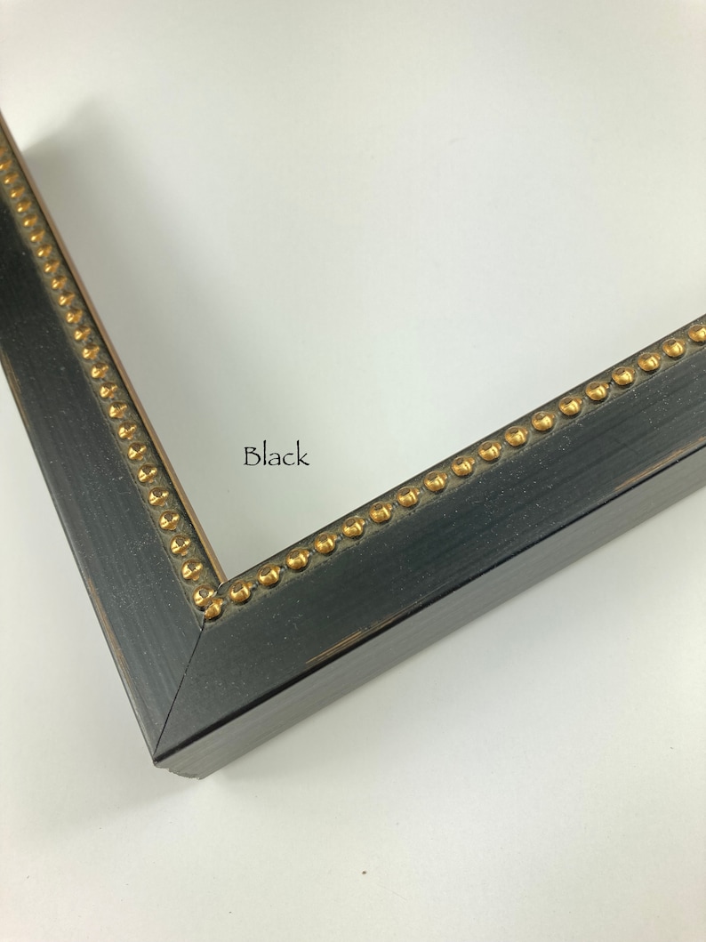 May include: Close-up of a black picture frame with gold accents. The frame has a distressed finish and a beaded edge.