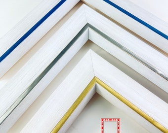 May include: Three white picture frames with different colored trim. The top frame has a blue trim, the middle frame has a silver trim, and the bottom frame has a gold trim. The frames are arranged in a triangular shape. The text "Fernwood Frames" is visible at the bottom of the image.
