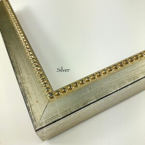 May include: Close-up of a silver picture frame with a beaded edge. The frame has a distressed finish and the word "Silver" is printed on the frame.