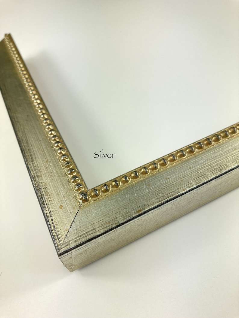 May include: Close-up of a silver picture frame with a beaded edge. The frame has a distressed finish and the word "Silver" is printed on the frame.