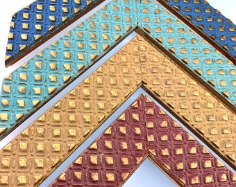 May include: Four picture frames with a diamond pattern, layered on top of each other. The frames are painted in shades of blue, teal, gold, and red.