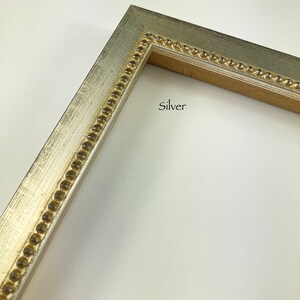 May include: Close-up of a silver picture frame with a gold beaded trim. The frame is on a white background. "Silver" is written in black text on the frame.