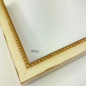 May include: Close-up of a white picture frame with a gold beaded trim. The frame is labelled "White".