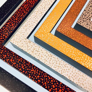 May include: A set of five picture frames with different colored polka dot patterns. The frames are arranged in a staggered pattern, with the largest frame at the bottom and the smallest frame at the top. The frames are all made of wood and have a black border.