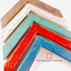 May include: Five different colors of distressed wood picture frames stacked on top of each other. The frames are in shades of gray, white, teal, red, and blue. The bottom frame has the text "Fernwood Frames" printed on it.