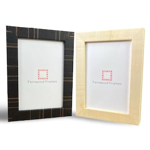 May include: Two picture frames, one black with a wood grain pattern and one natural wood color. Both frames have a white mat and the text "Fernwood Frames" printed on the mat.