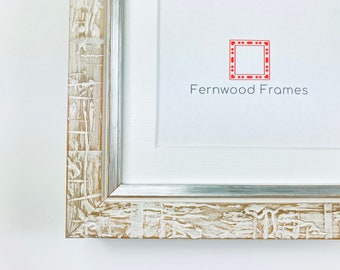 May include: Close-up of a rectangular picture frame with a distressed, textured finish. The frame has a light brown base with white paint accents and a silver inner edge. The text "Fernwood Frames" is visible on the white background.