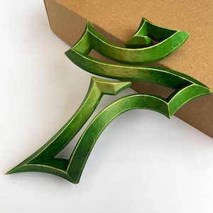Peut inclure: Une croix en bois verte avec un design abstrait unique. La croix est faite de plusieurs couches de bois, cr&eacute;ant un effet tridimensionnel.