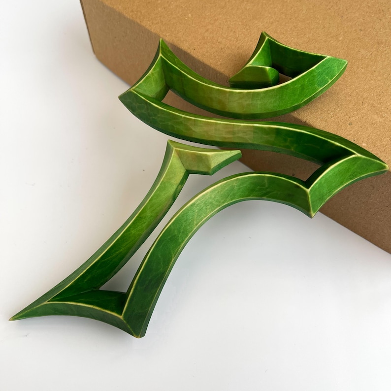 Peut inclure: Une croix en bois verte avec un design abstrait unique. La croix est faite de plusieurs couches de bois, cr&eacute;ant un effet tridimensionnel.