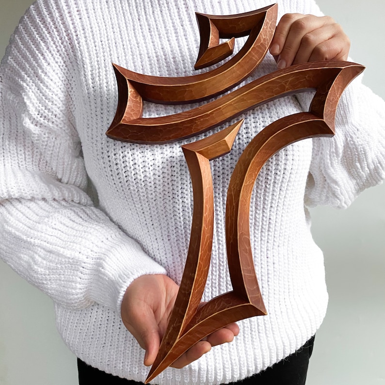 Peut inclure: Une croix en bois avec un design unique et complexe. La croix est en bois brun clair avec une teinte l&eacute;g&egrave;rement rouge&acirc;tre. Elle a une apparence tridimensionnelle et en couches, cr&eacute;ant un sentiment de profondeur et de texture.