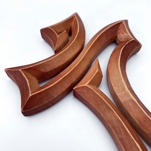Peut inclure: Une pi&egrave;ce d&eacute;corative en bois avec un design unique et complexe. La pi&egrave;ce est compos&eacute;e de deux formes courbes entrelac&eacute;es, cr&eacute;ant un motif complexe. Le bois a une couleur riche brun rouge&acirc;tre.