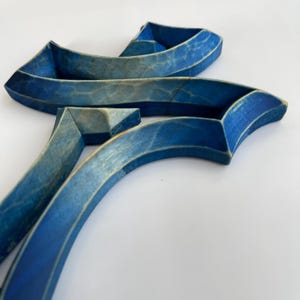 Peut inclure: Sculpture en bois bleu compos&eacute;e de plusieurs pi&egrave;ces courbes. La sculpture est abstraite et ressemble &agrave; une lettre stylis&eacute;e.