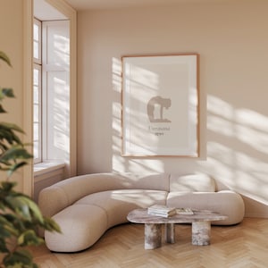 Könnte beinhalten: Ein hellbeiges, geschwungenes Sofa mit einem Holz-Couchtisch in einem Raum mit einem großen Fenster und einem gerahmten Druck einer Yoga-Pose namens "Ustrasana" mit dem Sanskrit-Wort für die Pose darunter.