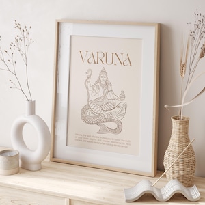 Könnte beinhalten: Gerahmter Kunstdruck mit dem Wort "VARUNA" und einer Illustration einer Gottheit. Das Kunstwerk ist in Braun- und Beigetönen gehalten, mit Text unten. Es wird auf einer Holzoberfläche mit dekorativen Vasen präsentiert.