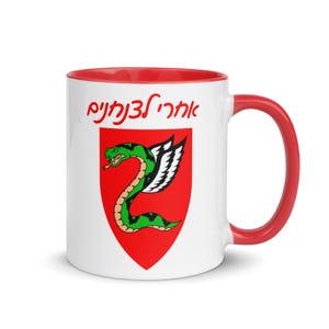 May include: White ceramic mug with a red rim and handle. The mug features a red shield with a green winged snake and the Hebrew text "אהבה נצחית" (Eternal Love).