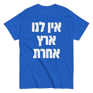Può includere: Una t-shirt blu reale con le parole ebraiche "Ani Ohev Attah" stampate in bianco. Le parole sono in uno stile di font usurato.