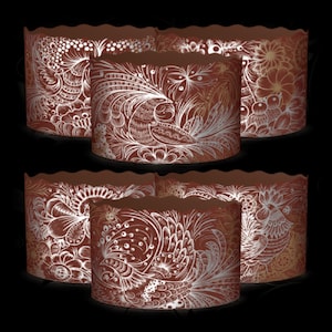 Puede incluir: Seis moldes para pasteles marrones y blancos con patrones y bordes festoneados. El patrón presenta un diseño blanco de pájaros y flores estilizados sobre un fondo marrón.
