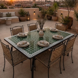 May include: A rectangular dining table with a green tiled top featuring a white geometric pattern, surrounded by six chairs with woven seats and black metal frames. The table is set with white plates, napkins, and green glassware.
