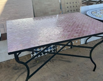 Könnte beinhalten: Ein quadratischer Tisch mit einer rosa gefliesten Tischplatte und einem schwarzen Metallrahmen. Der Tisch hat ein schlichtes Design und steht auf einer Terrasse.