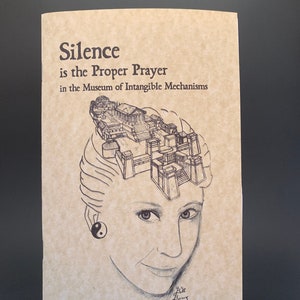 May include: A tan-colored booklet with the text "Silence is the Proper Prayer in the Museum of Intangible Mechanisms." The cover features a pencil sketch of a woman with a building design atop her head and a yin-yang earring.