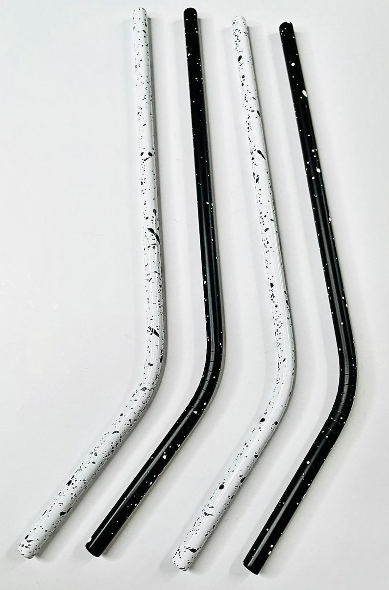 May include: Four reusable metal straws. Two are white with black speckles, and two are solid black. All straws have a curved design and are made of metal. The straws are designed for drinking beverages.
