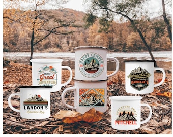 Puede incluir: Seis tazas de camping de esmalte blanco con bordes y asas negros. Las tazas presentan diferentes diseños con temática de montaña con texto que incluye "Happy Camper", "Melissa's Great Adventure", "Landon's Adventure Mug", "Adventure Awaits Mitchell", "Adventure is Waiting Danielle's" y "Going to the Mountains".