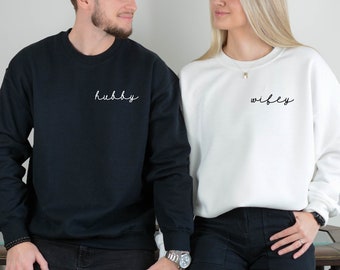 Peut inclure: Un couple portant des sweat-shirts assortis noir et blanc avec les mots "hubby" et "wifey" brodés dessus.