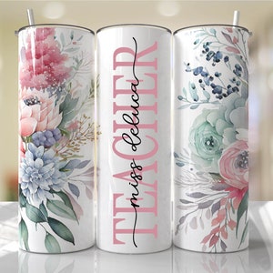 May include: Three stainless steel tumblers with floral designs. The middle tumbler has the text "TEACHER miss deluca" in pink and black lettering.