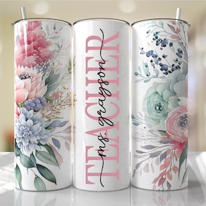May include: Three stainless steel tumblers with floral designs. The middle tumbler has the text "TEACHER" in black with "mrs. grayson" in pink underneath.